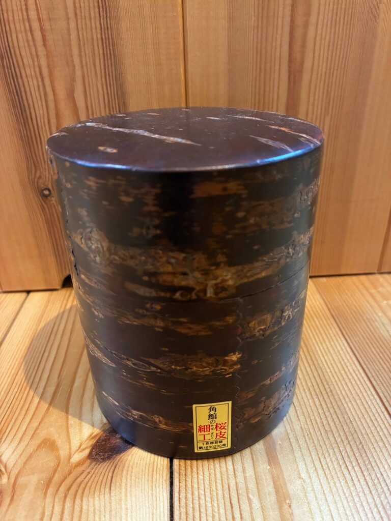 A traditional Japanese Kabazaiku tea caddy made from natural cherry bark, placed on a wooden surface.